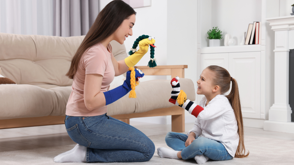 Happy mother and daughter playing with funny sock puppets together at home