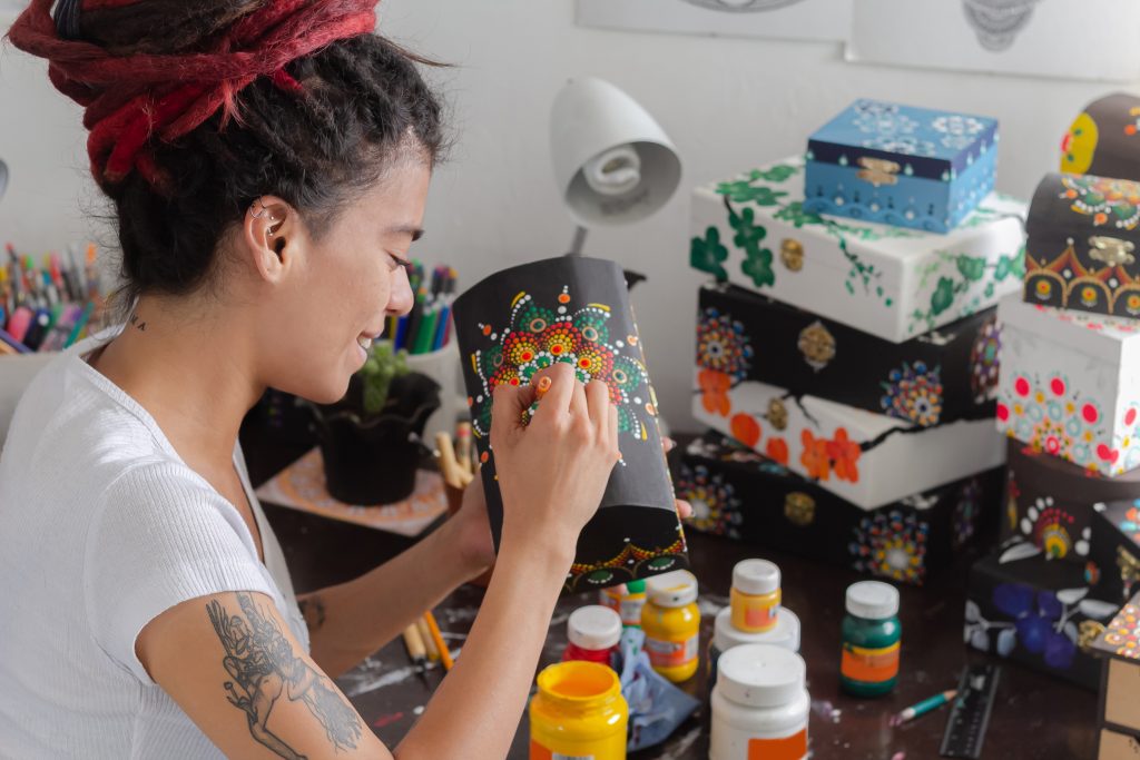 woman sitting with dreadlocks making handcrafts at home