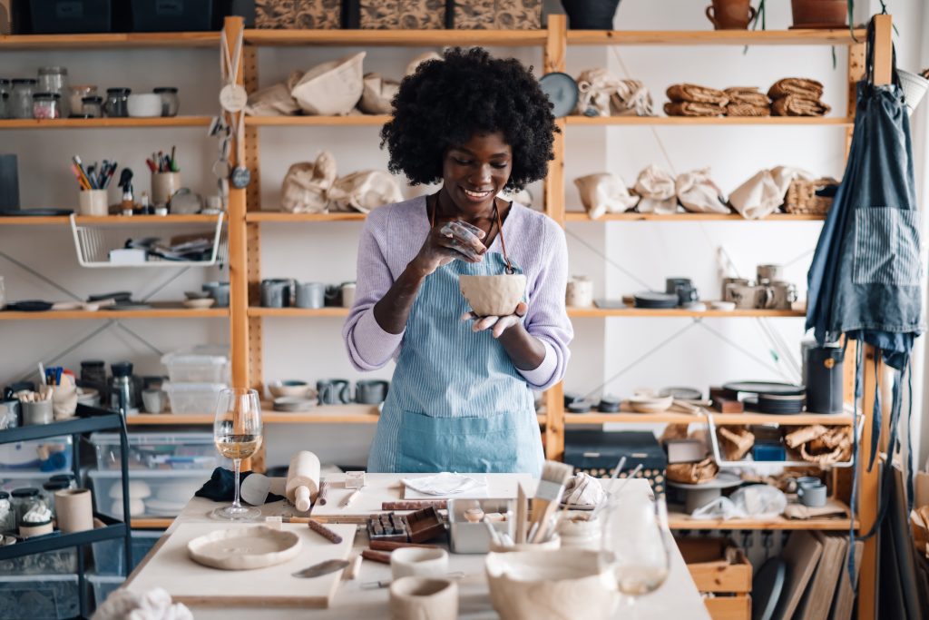 Interracial craftswoman at pottery workshop decorating clay work.